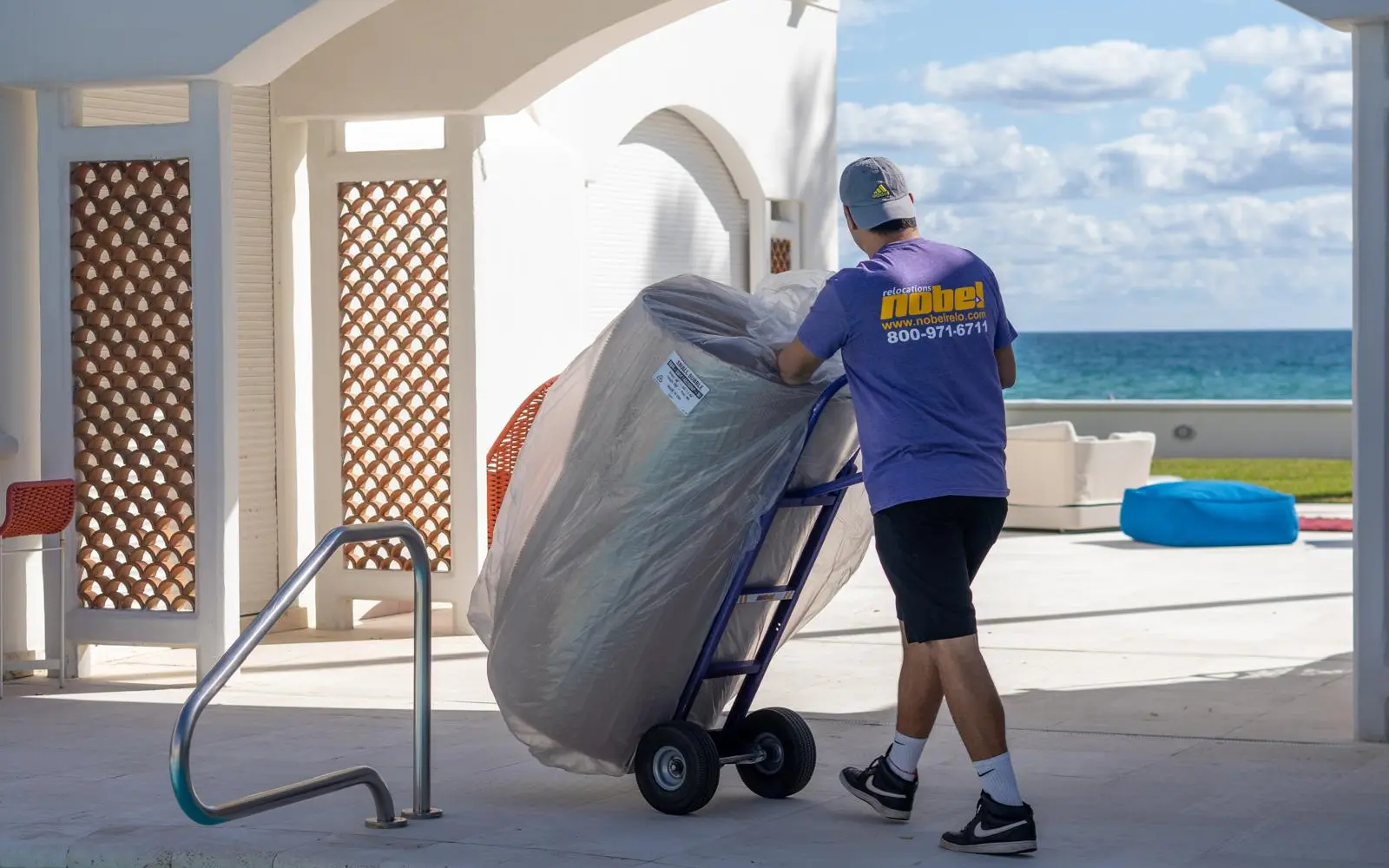 Nobel Relocation mover handling wrapped furniture at an oceanfront home in Miami