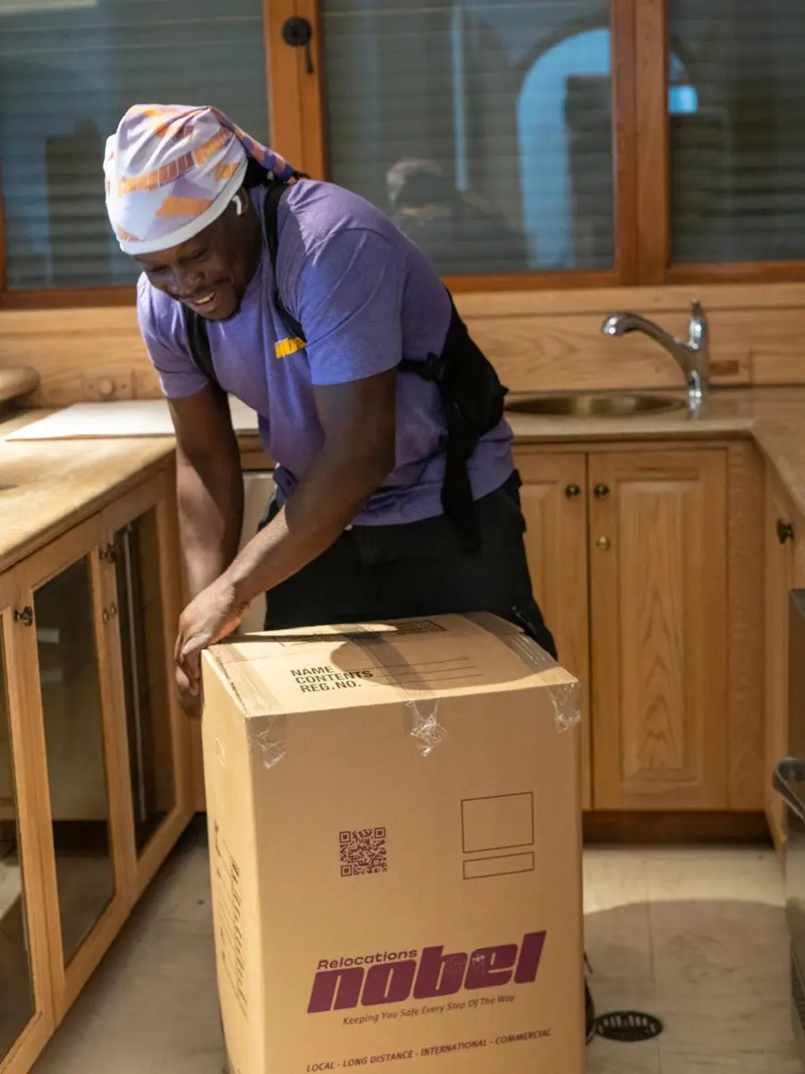 Nobel Relocation mover packing a branded moving box in a Miami home